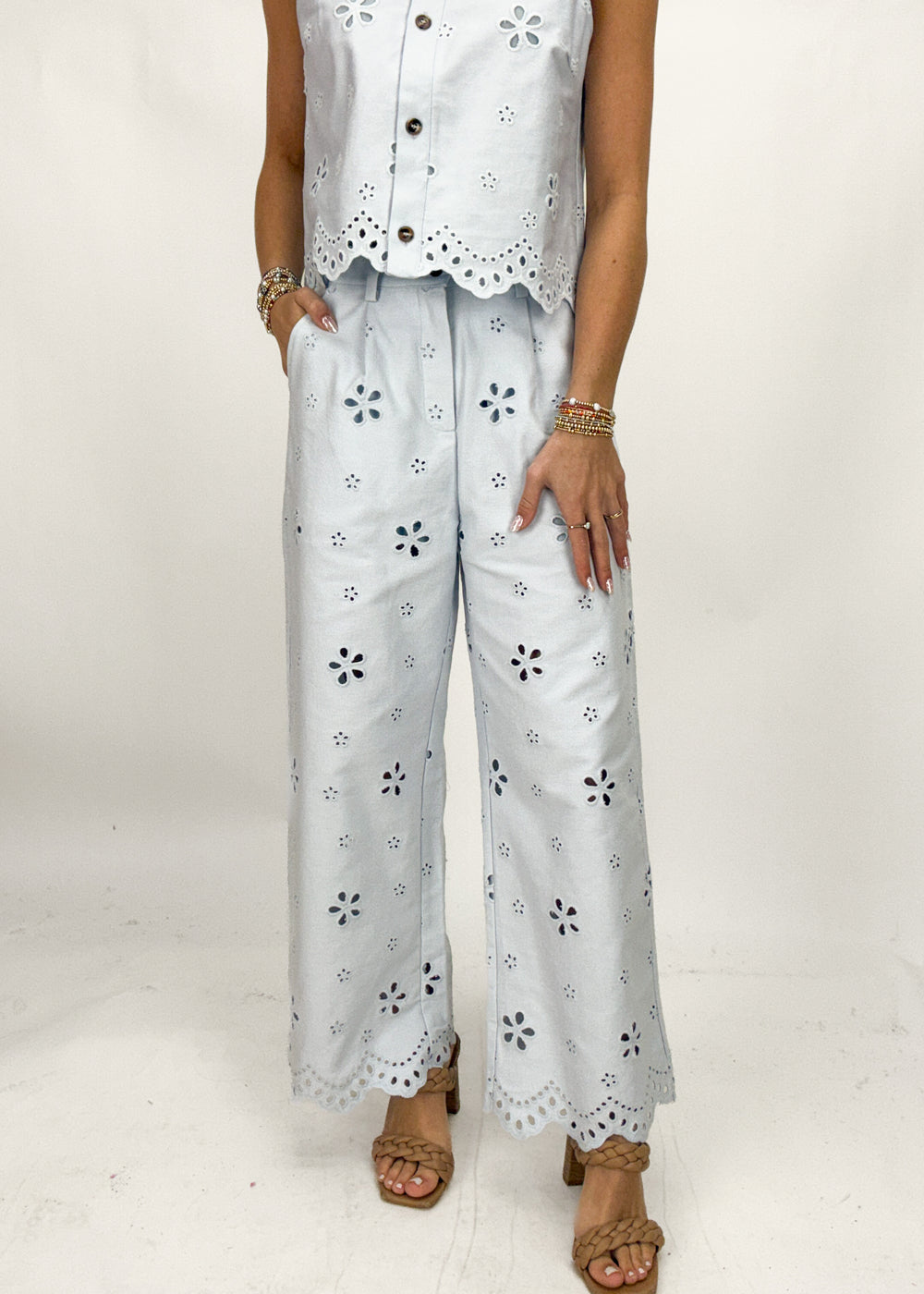 Person wearing a white outfit with floral cut-out details on a plain background