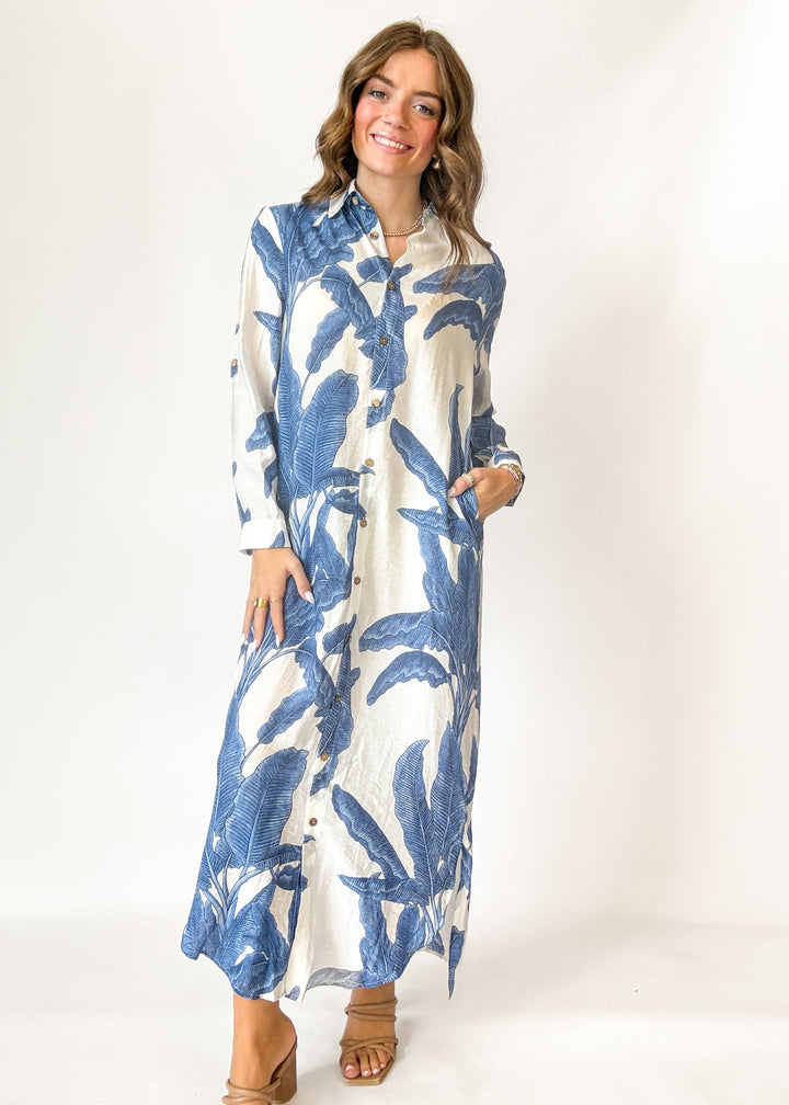 Woman wearing a long blue and white floral dress on a white background