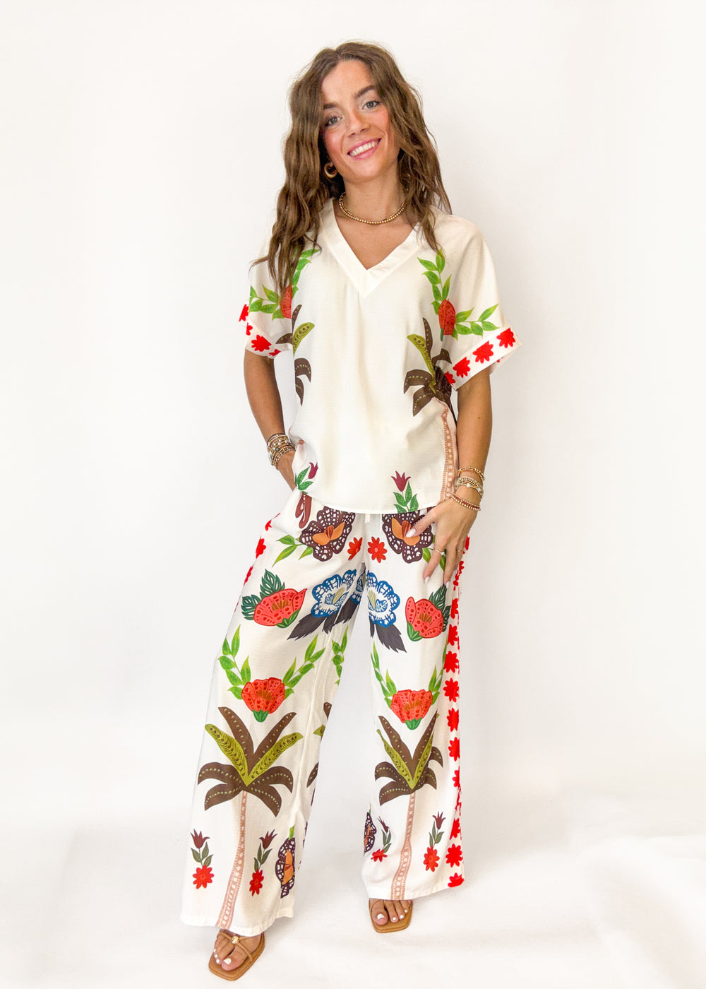 Woman wearing a white outfit with colorful floral patterns on a white background