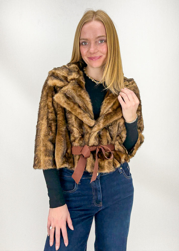 Woman wearing a brown faux fur coat with a belt 