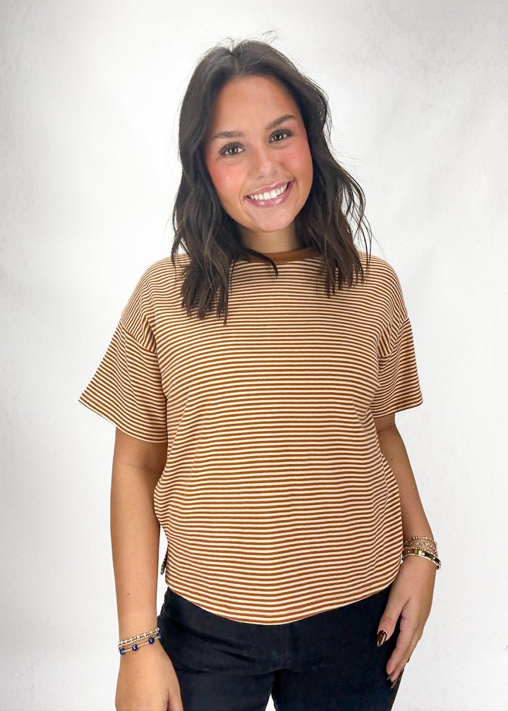 Woman wearing a brown striped shirt against a white background