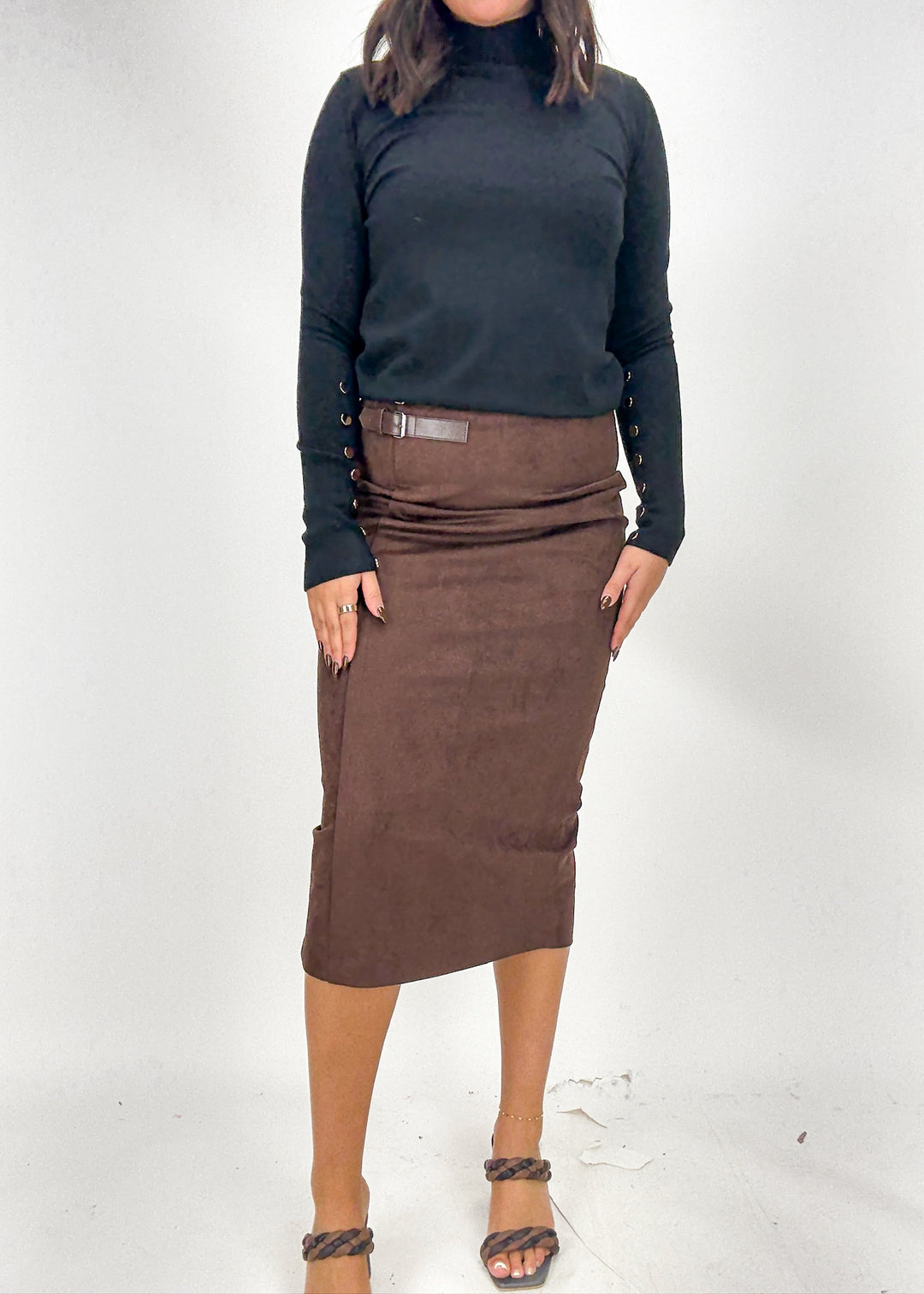 Person wearing a black turtleneck and brown skirt on a white background