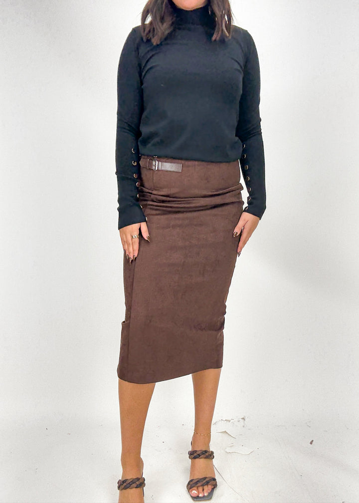 Person wearing a black turtleneck and brown skirt on a white background