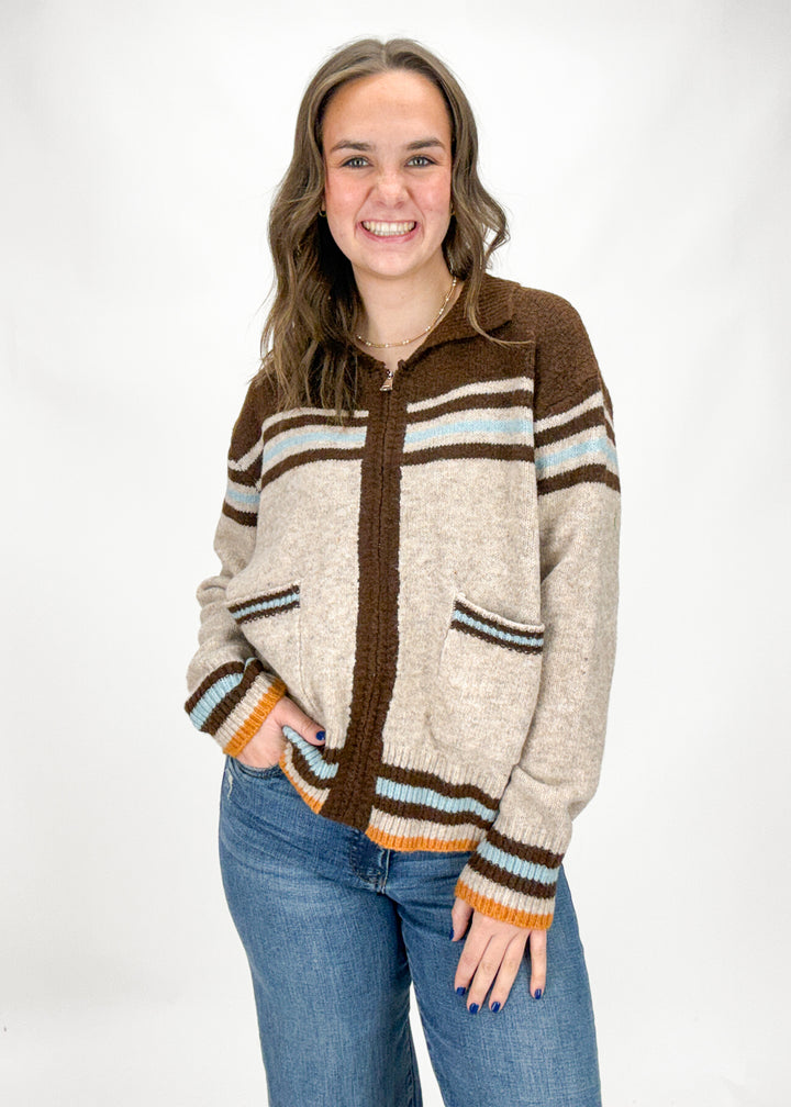 Woman wearing a brown and beige striped sweater with a white background