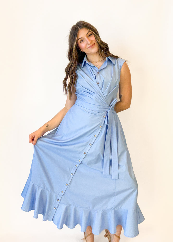 Woman wearing a light blue dress with buttons on a plain background