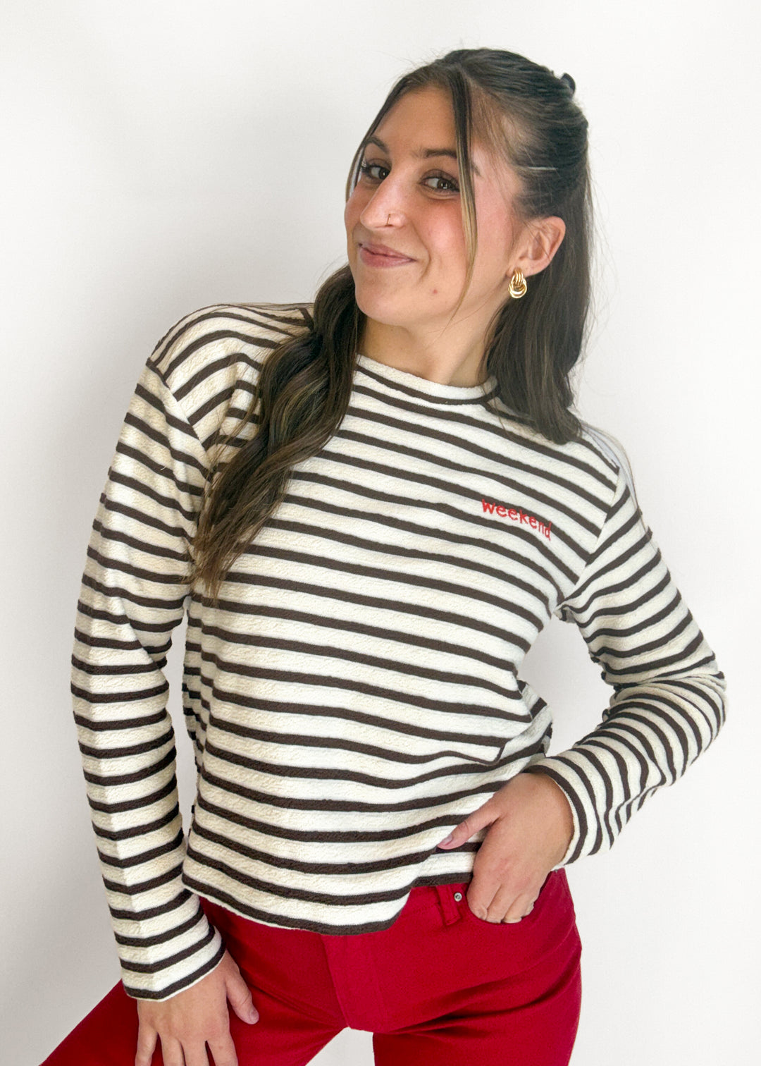 Woman wearing a cream and brown stripe long sleeve top with the words 'weekend' on the chest