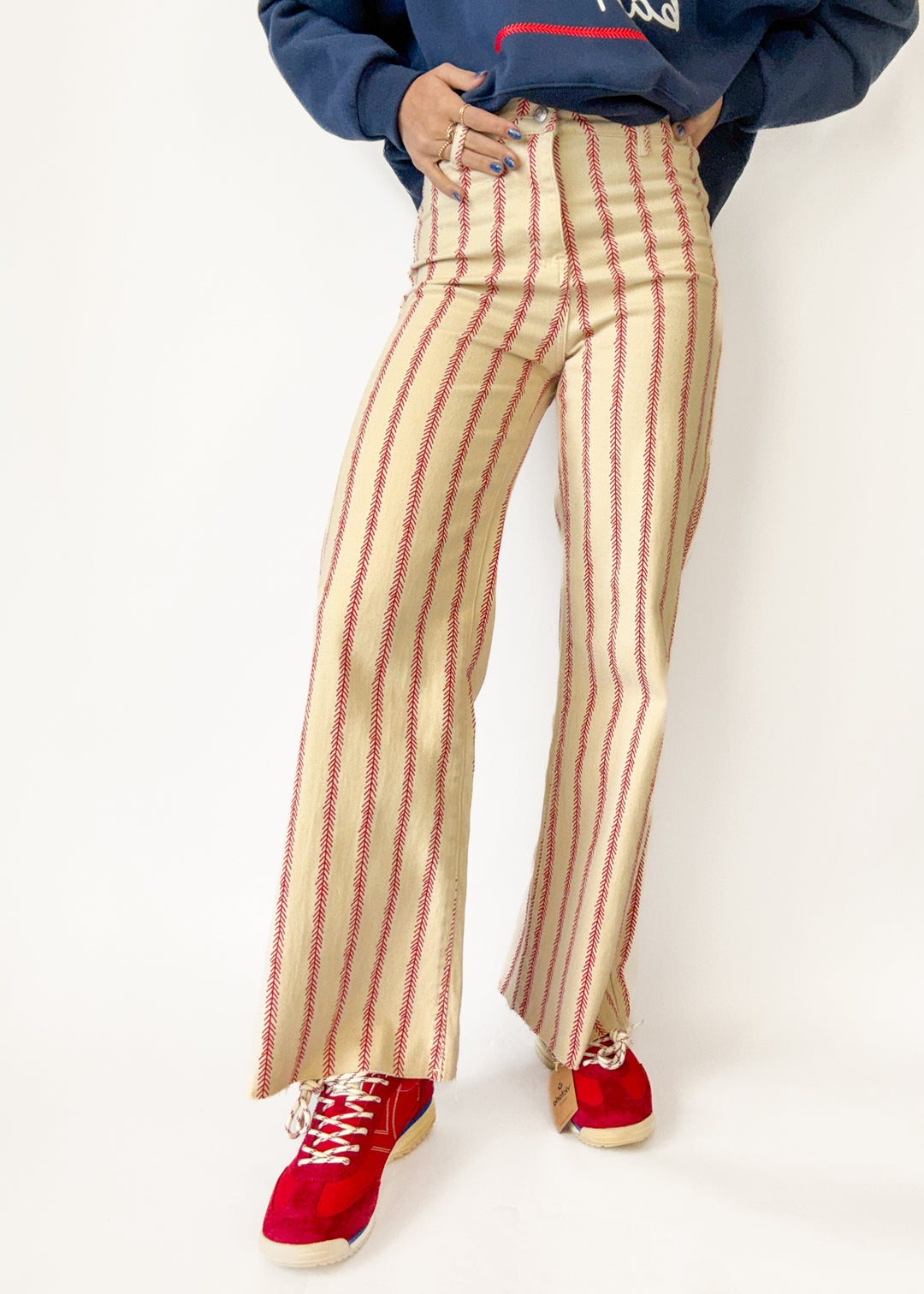 Person wearing red and beige striped pants with a blue sweatshirt on a white background
