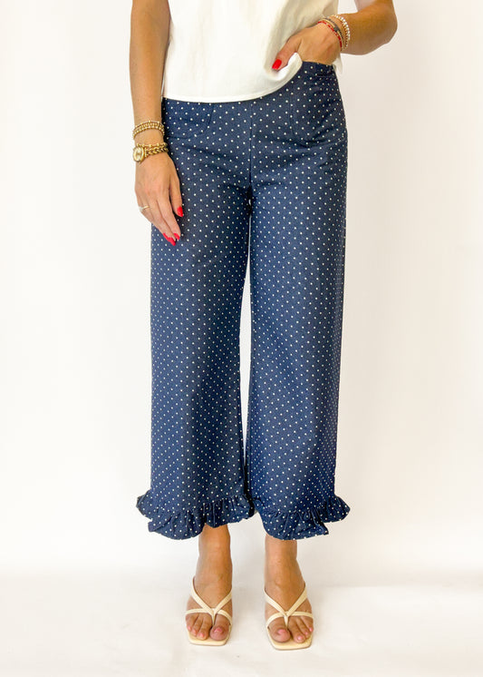 Woman wearing navy blue polka dot pants on a white background