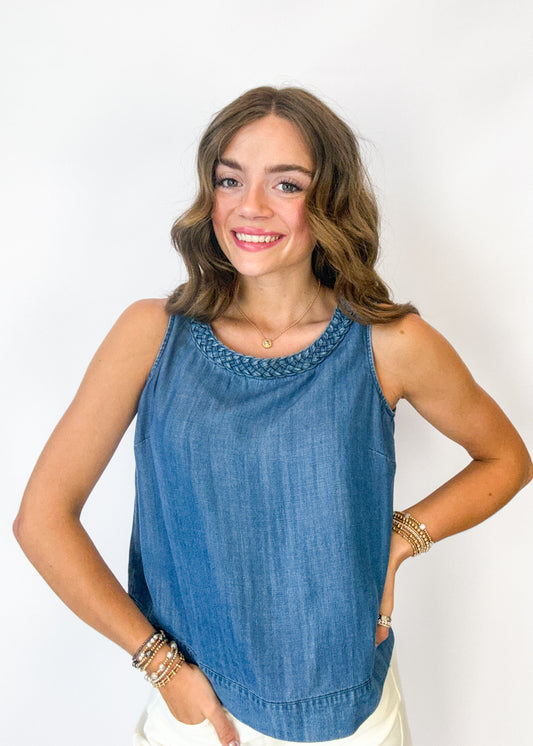 Woman wearing a blue sleeveless top with a white background
