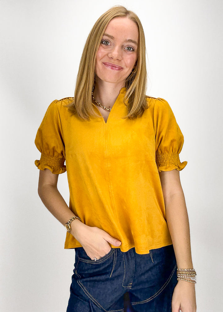 Woman wearing a mustard yellow blouse with puffed sleeves 