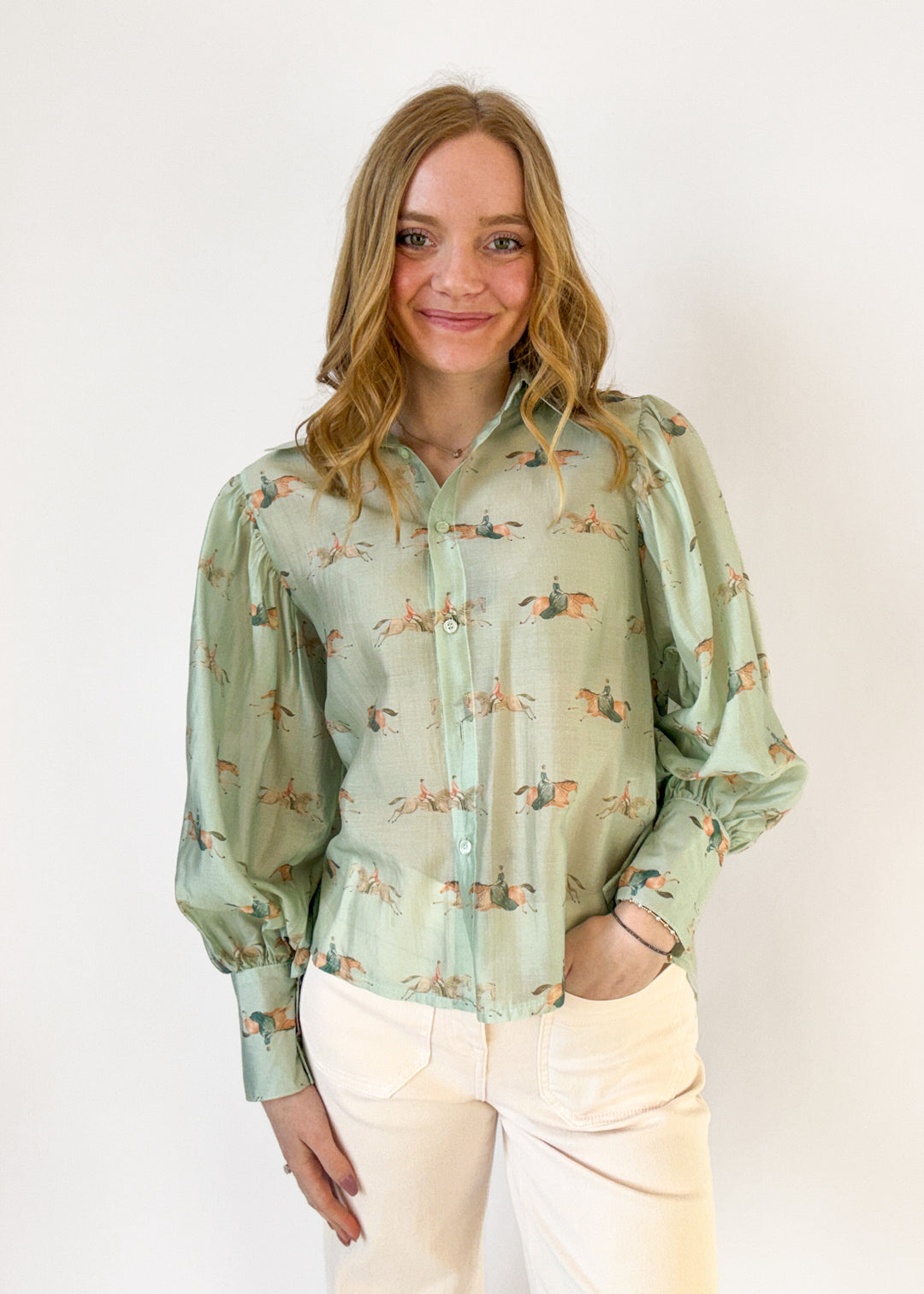 Woman wearing a light green blouse with a subtle pattern against a white background