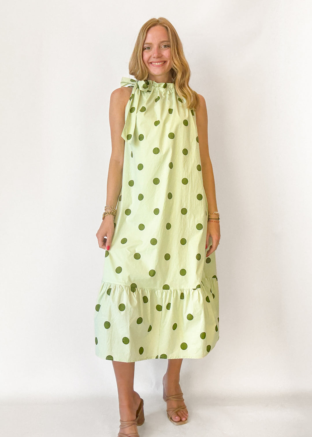 Woman wearing a light green dress with dark green polka dots on a white background