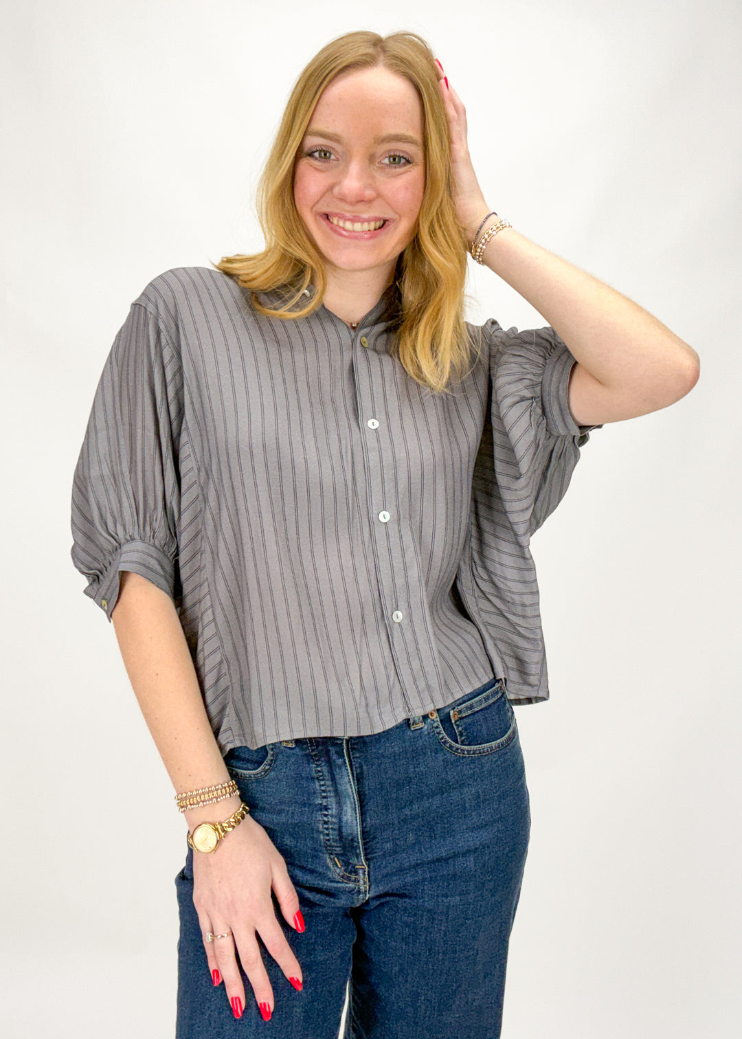 Woman wearing a gray striped shirt and blue jeans on a white background