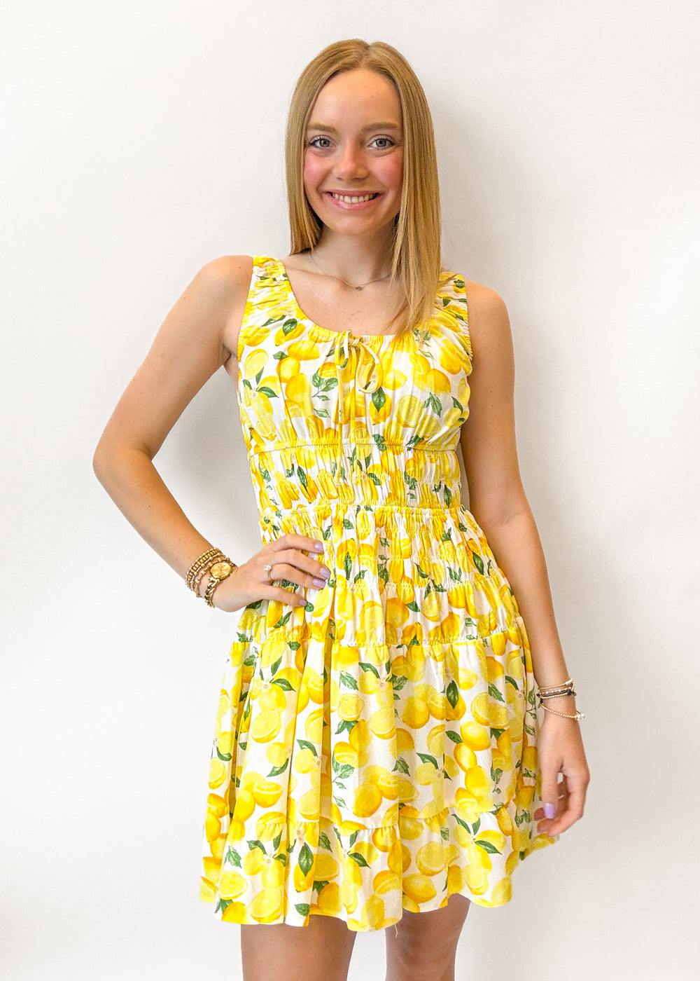 Woman wearing a yellow dress with lemon pattern against a white background