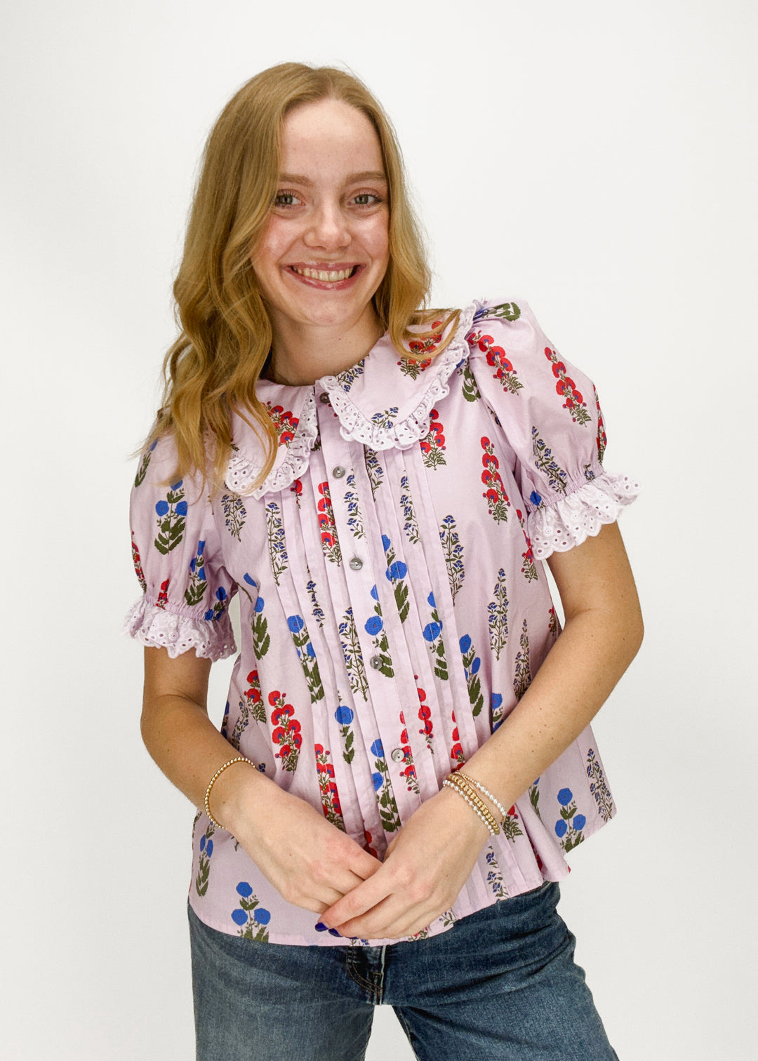woman wearing lilac purple puff sleeve top with lace trim collar and floral print