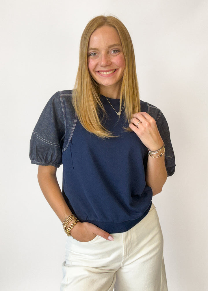 Woman wearing a navy and denim puff sleeve top