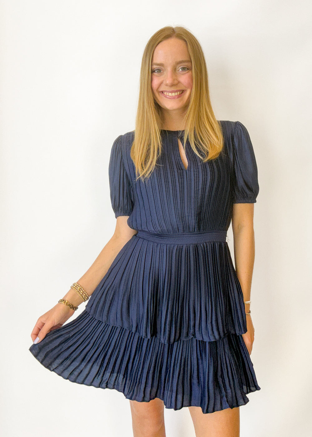 Woman wearing a navy blue pleated mini dress. 