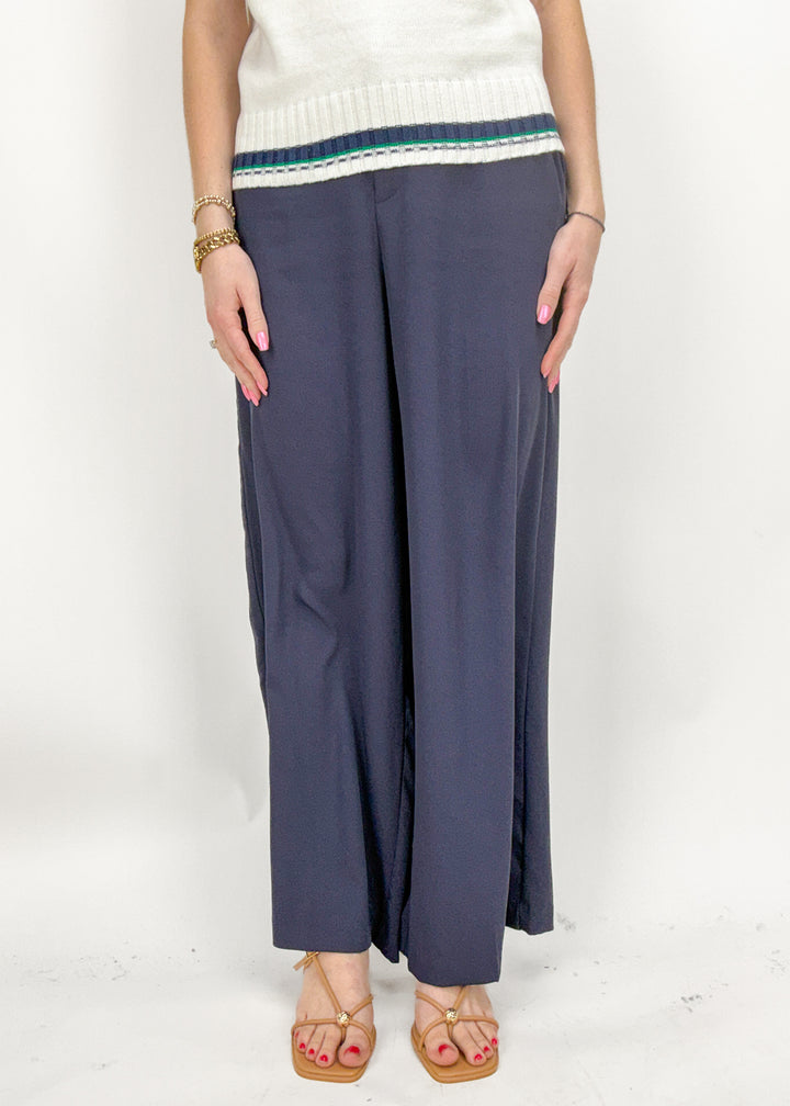 Person wearing navy wide-leg pants with a white top on a white background