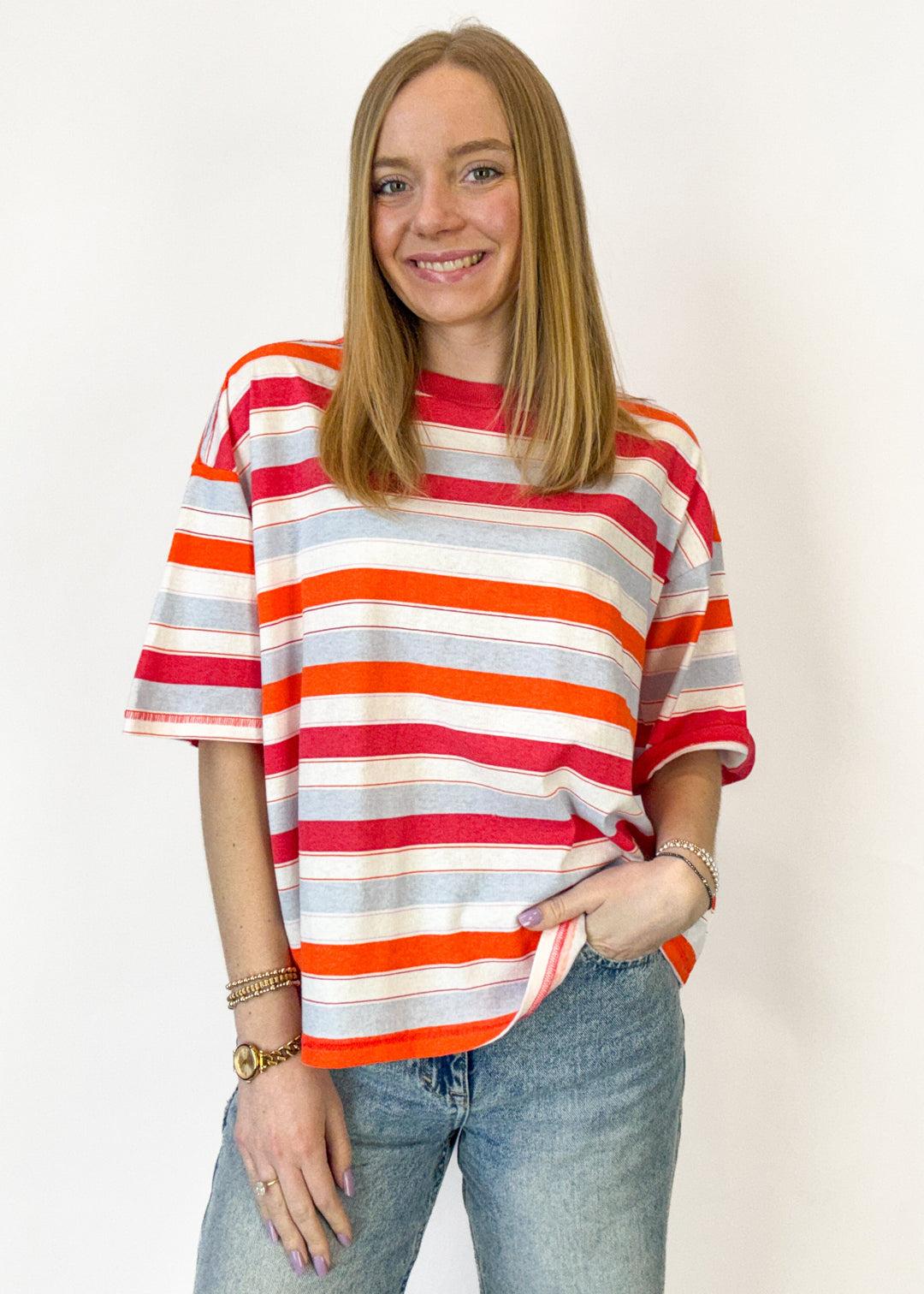Person wearing a striped shirt with red, orange, and white horizontal stripes on a plain background