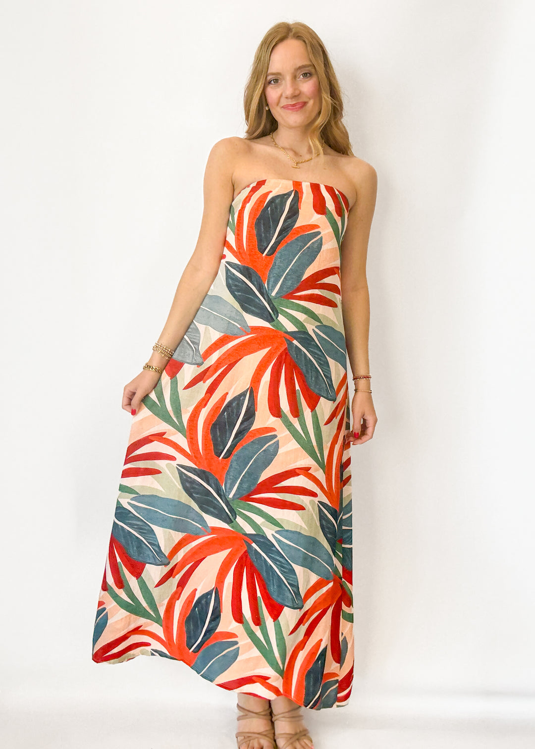 Woman wearing a strapless dress with a colorful leaf pattern on a white background