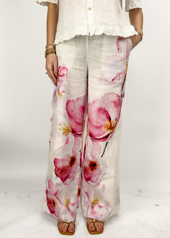 Person wearing floral pants with a white top on a white background