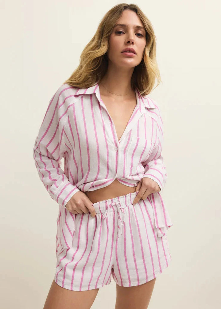 Woman wearing a pink and white striped pajama set against a beige background