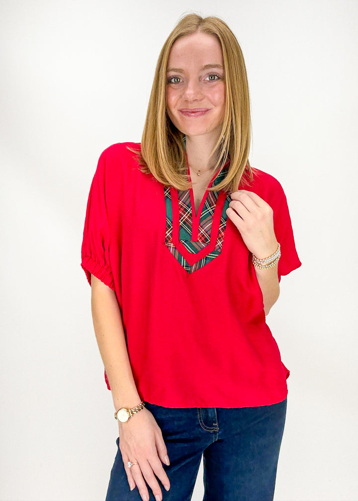 Woman wearing a red blouse with plaid accents 