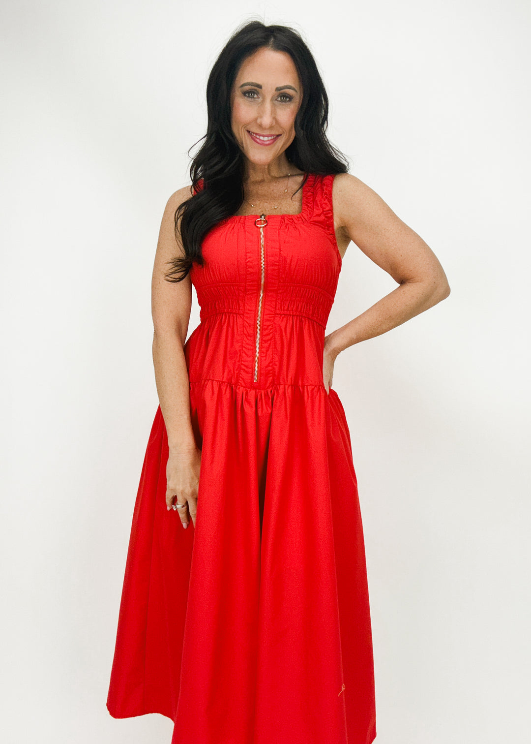 woman wearing red square neck tank top cinched waist midi dress with gold front zipper