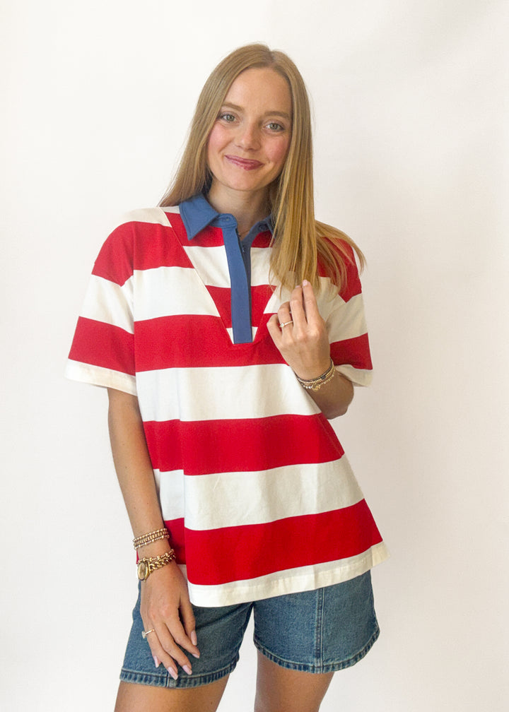 Woman wearing a red and white striped polo shirt with a blue collar on a white background
