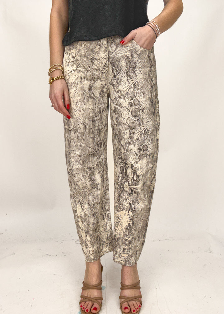 Person wearing snake print pants on a plain background