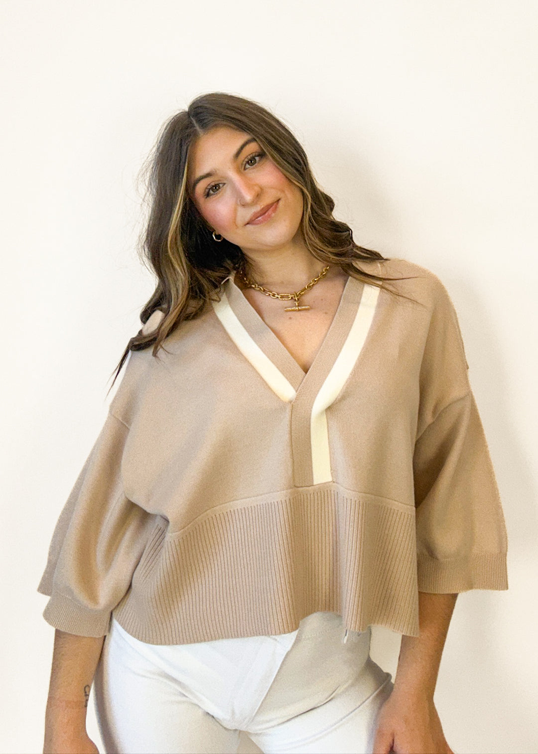 Woman wearing a beige sweater with reflective stripes on a white background