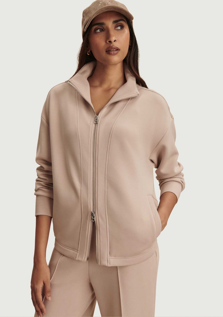 Woman wearing a beige tracksuit and cap on a light gray background