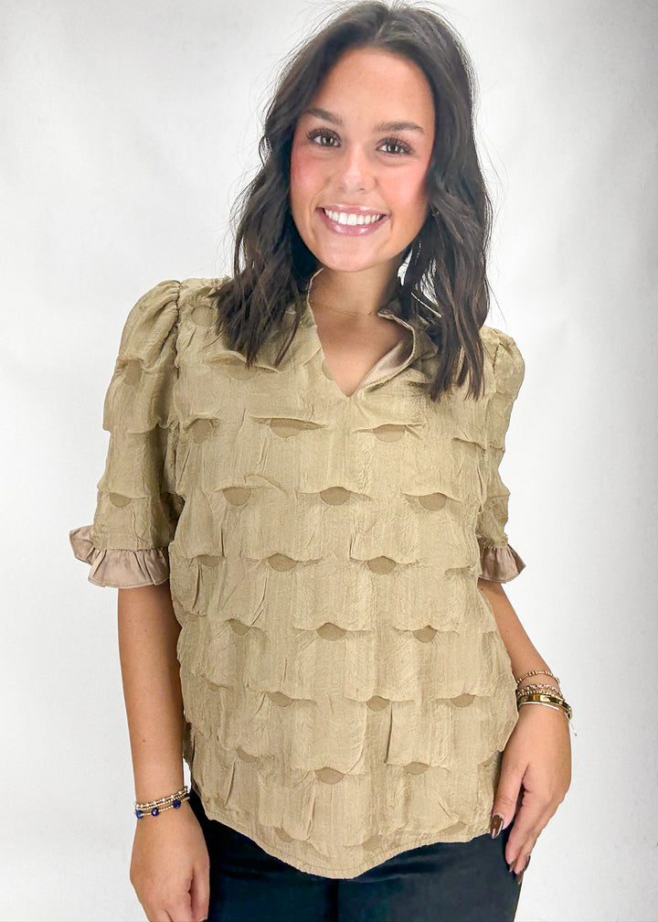 Woman wearing a beige ruffled blouse against a white background