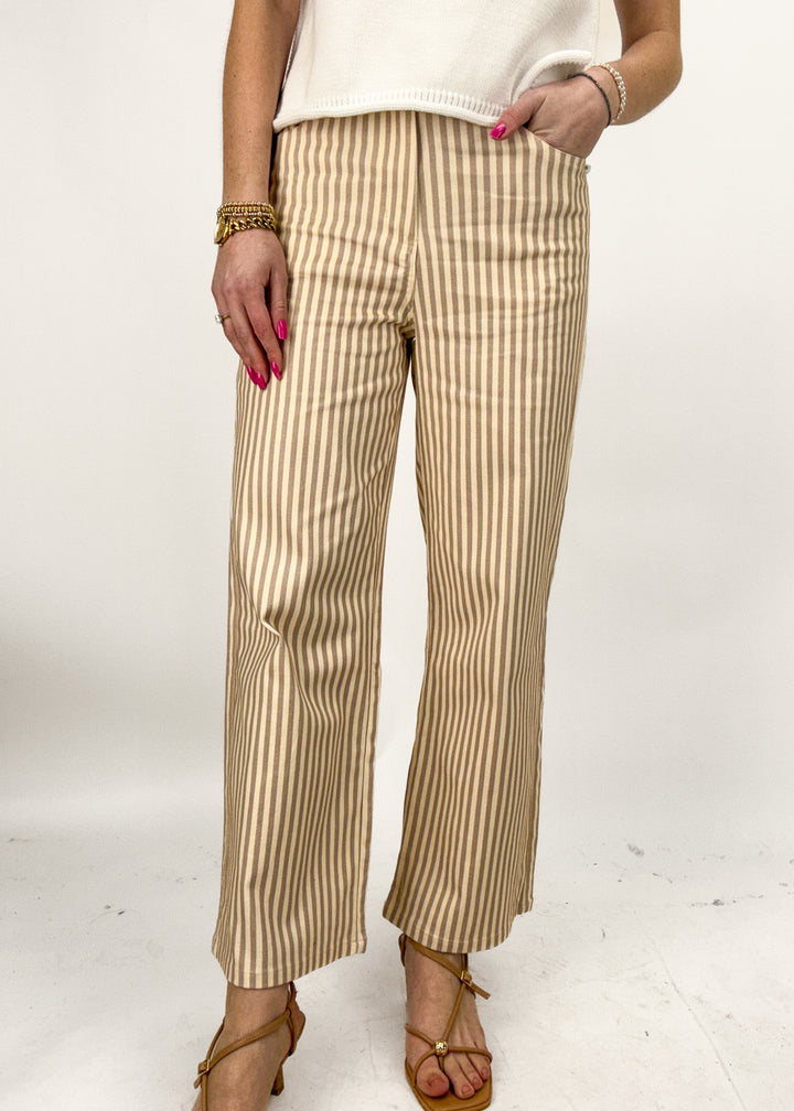 Beige and white striped pants worn by a person on a white background