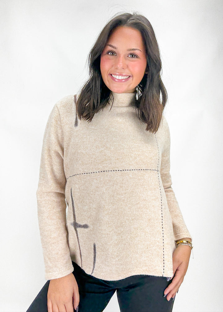 Woman wearing a beige sweater with a white background