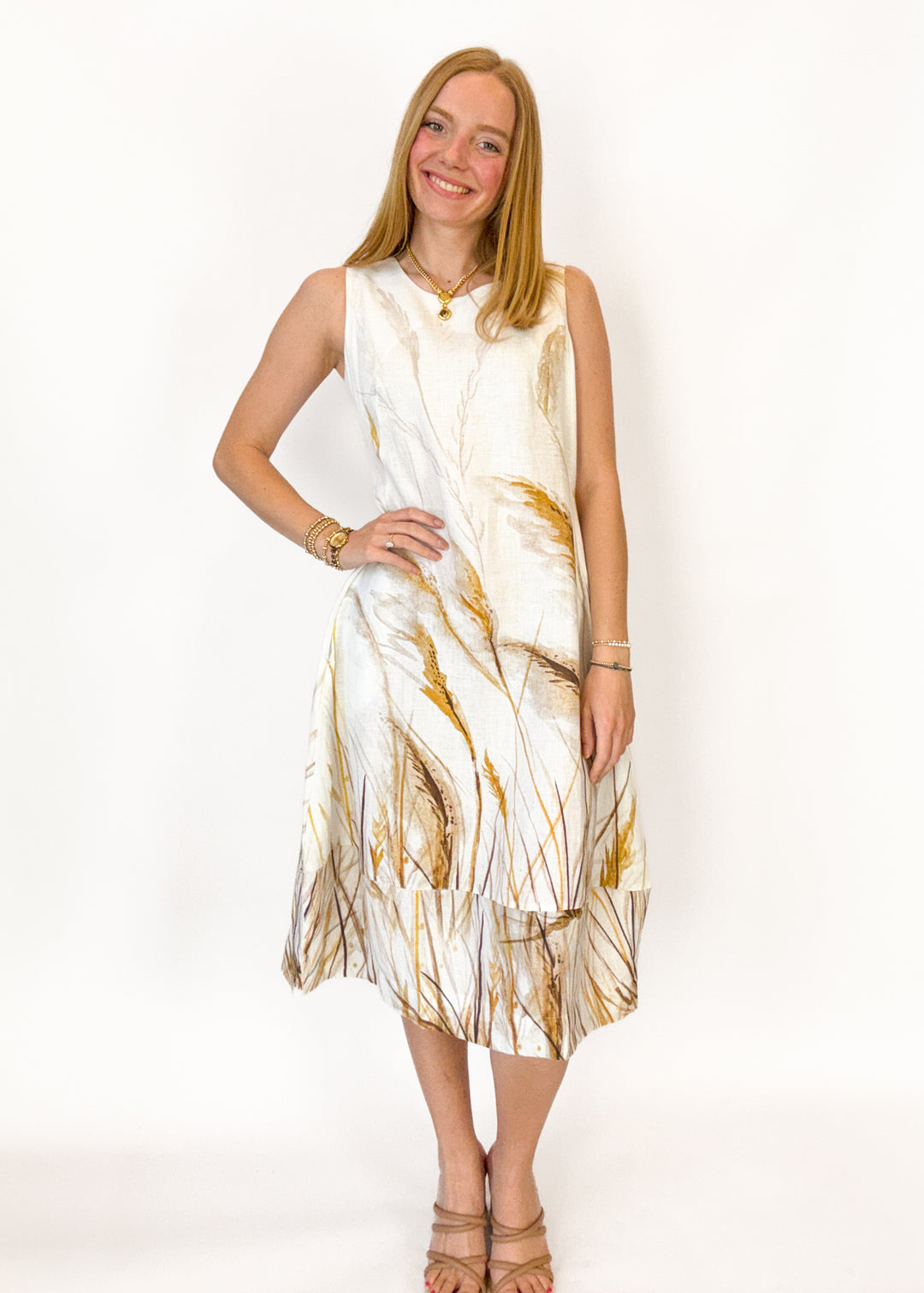 Woman wearing a sleeveless dress with gold abstract patterns on a white background