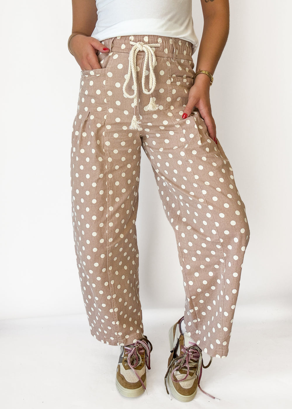 A person wearing loose, wide-leg cropped pants in a beige/tan base with white polka dots