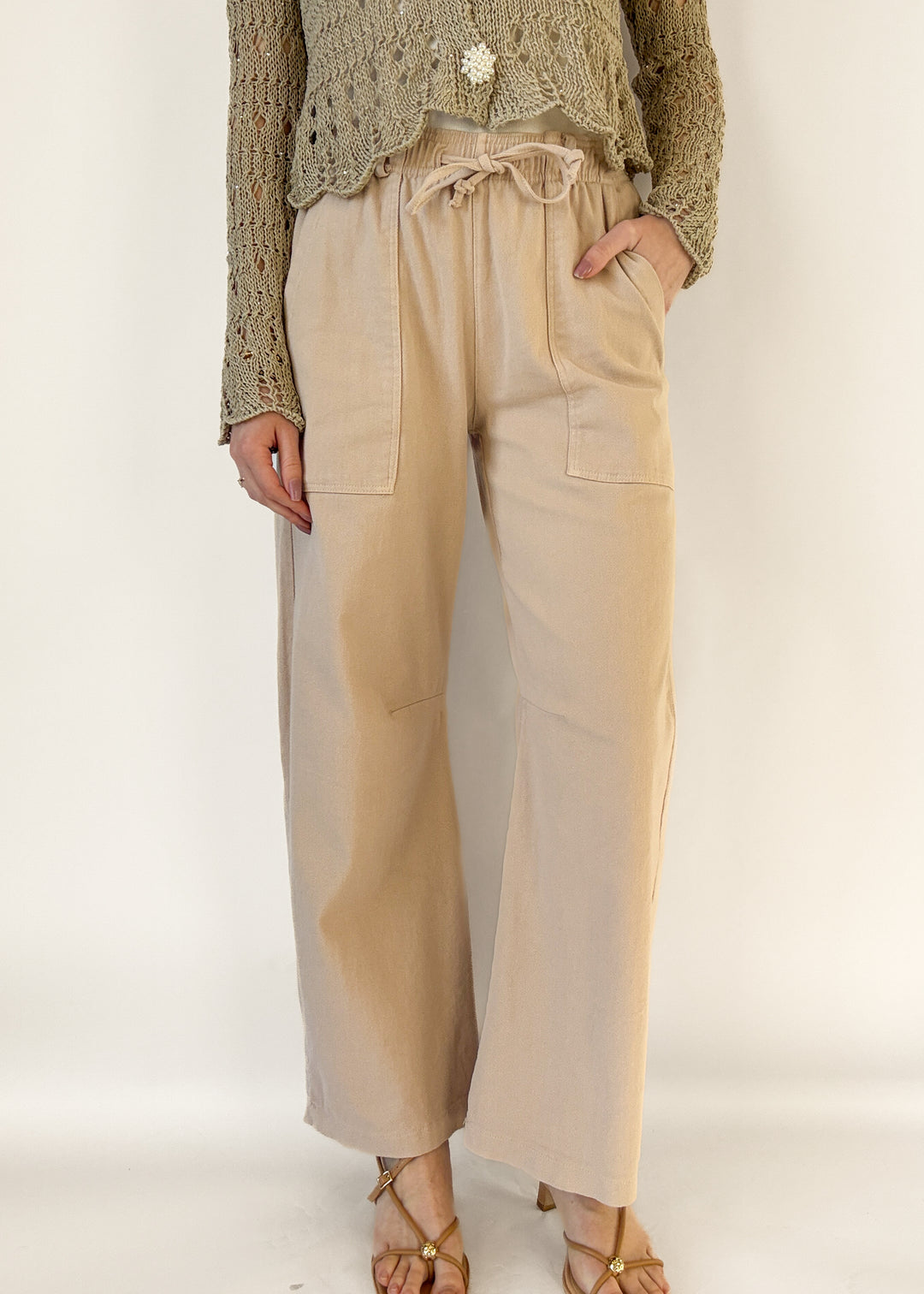 Person wearing blush pants and a textured sweater on a white background