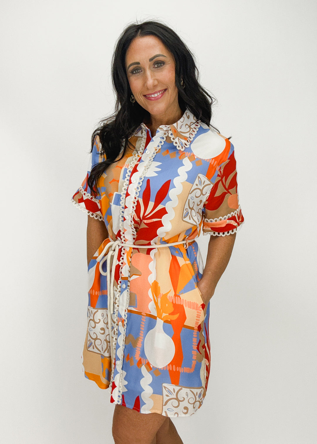 blue, red, orange, peach, white, and tan abstract print collared short sleeve button down mini dress with scallop trim details and waist tie
