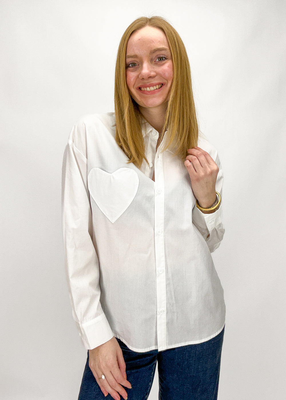 Woman wearing a white shirt with a heart design on a plain background