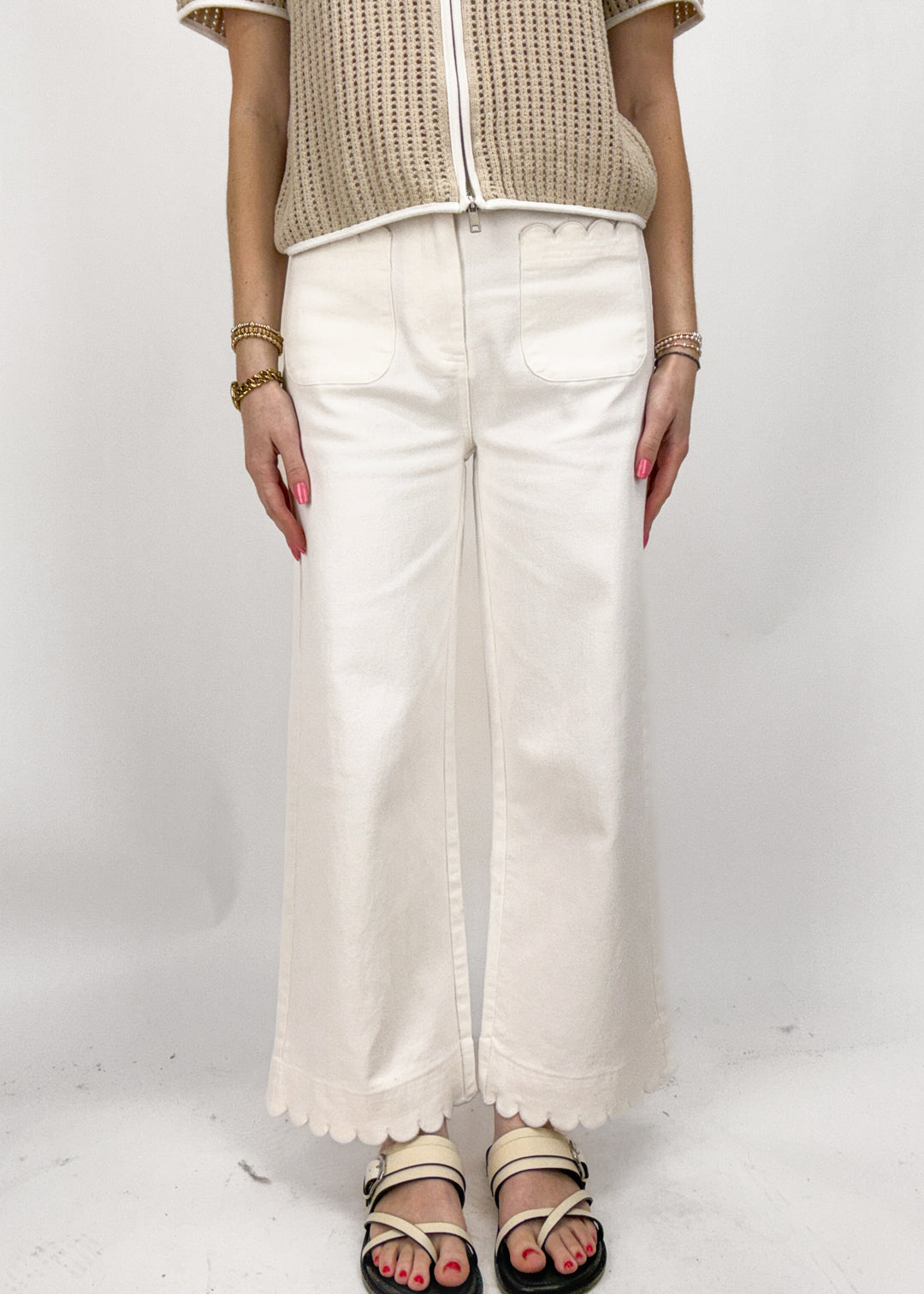 Person wearing a beige top and white pants on a white background