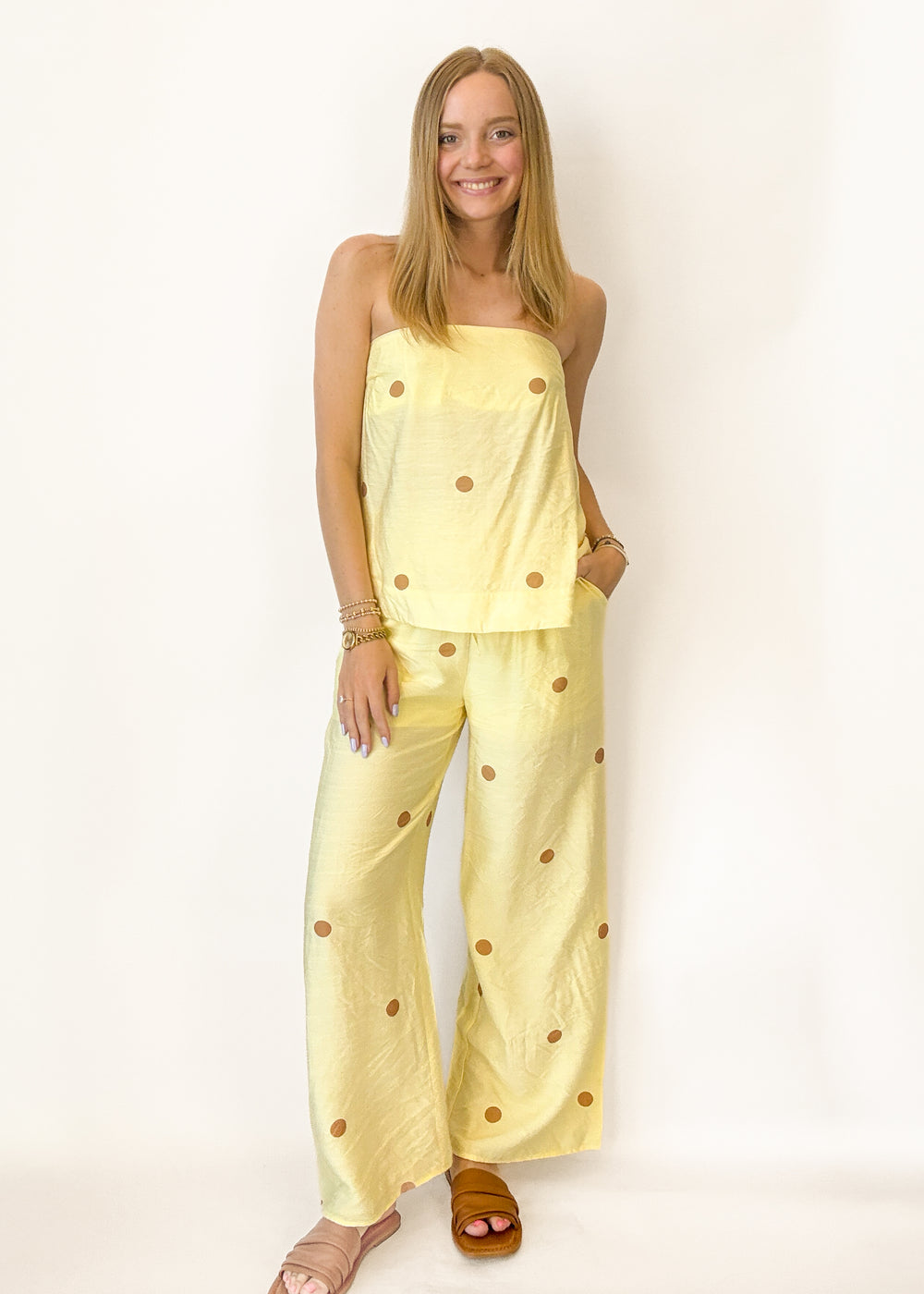 Woman wearing a yellow outfit with brown polka dots on a white background