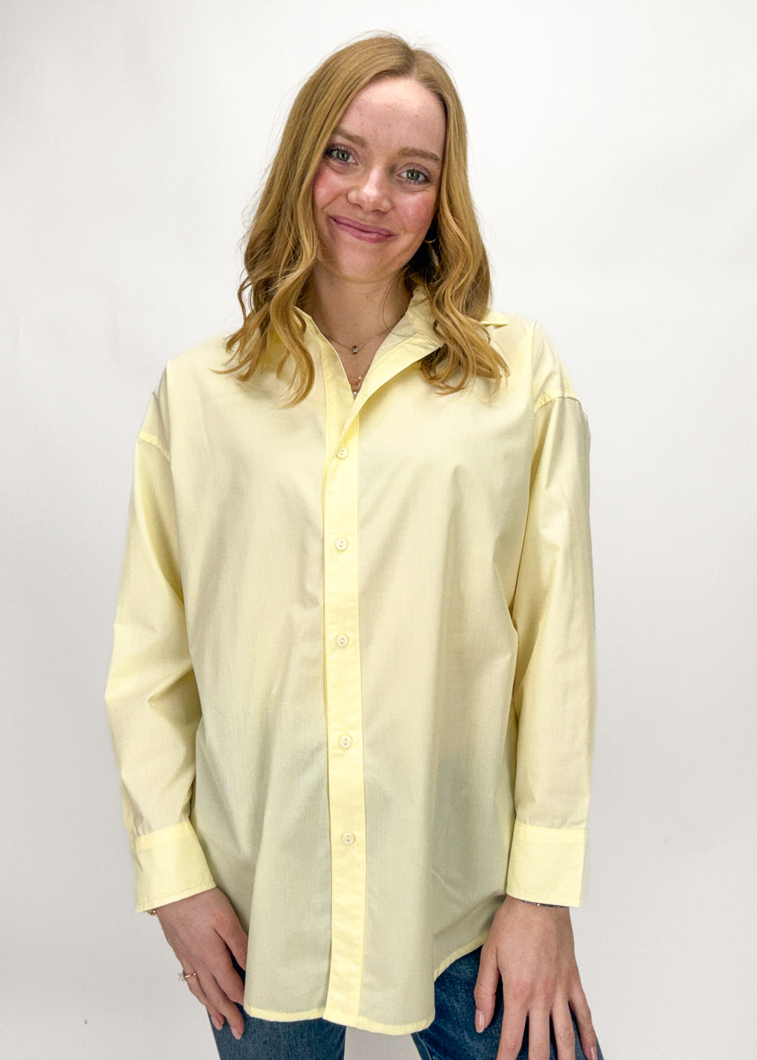 Woman wearing a light yellow button-up shirt against a white background