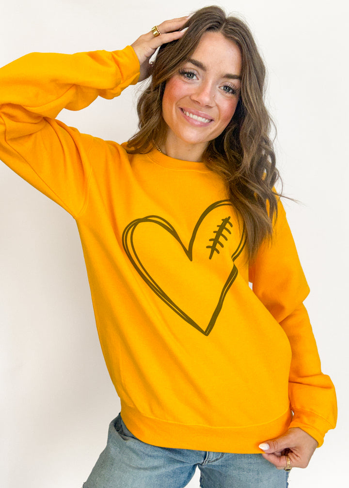 Woman wearing a yellow sweatshirt with a heart design on a plain background