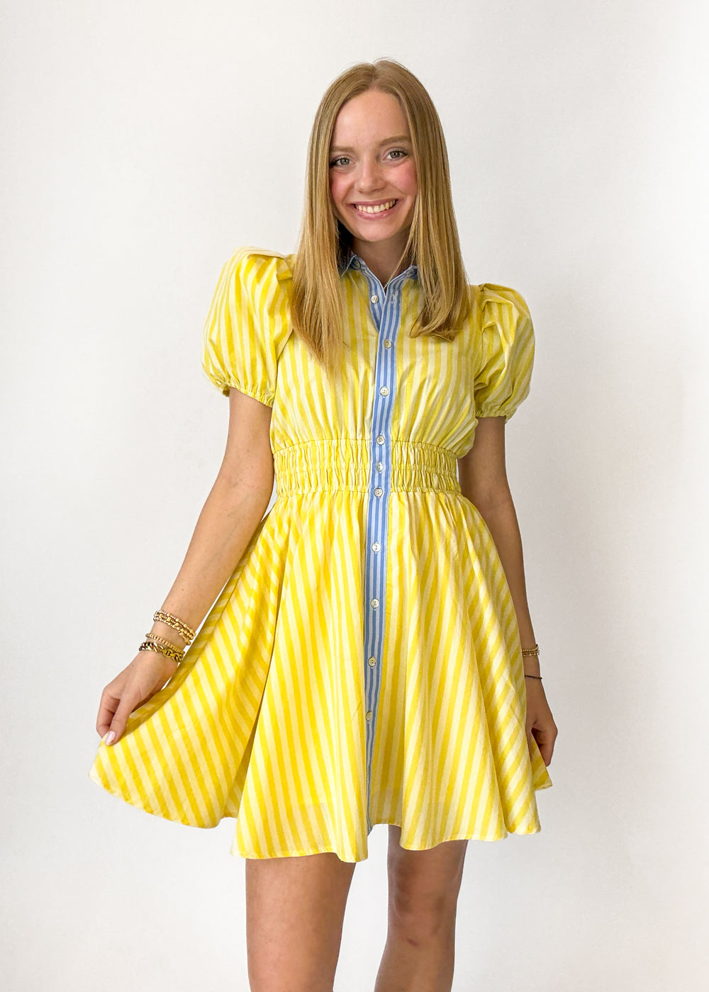 Woman wearing a yellow dress with puffed sleeves against a white background